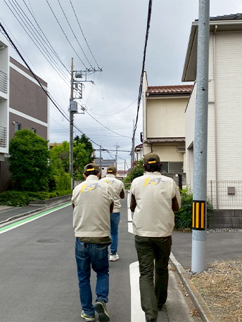 会社のユニフォームを着た3人の社員の背中